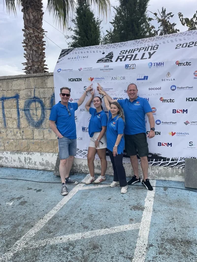 Volunteers in blue Maritime Events shirts pointing at the sponsor backdrop