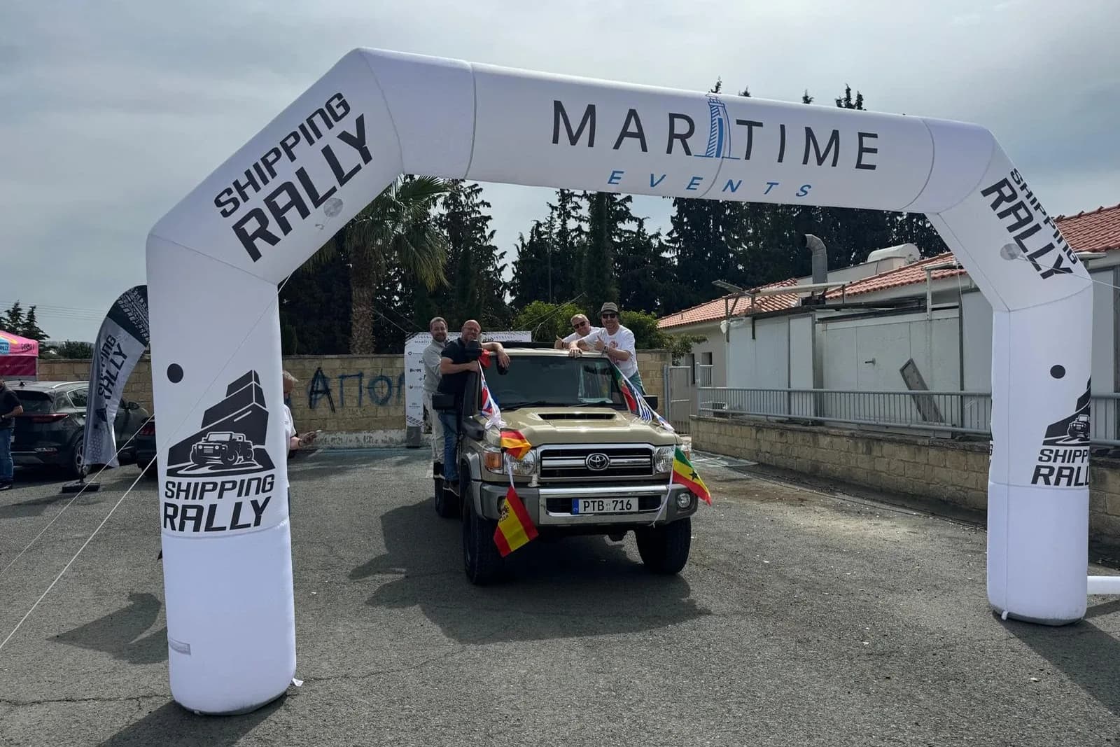 A Land Cruiser decked out in flags rolling under the Maritime Events start arch