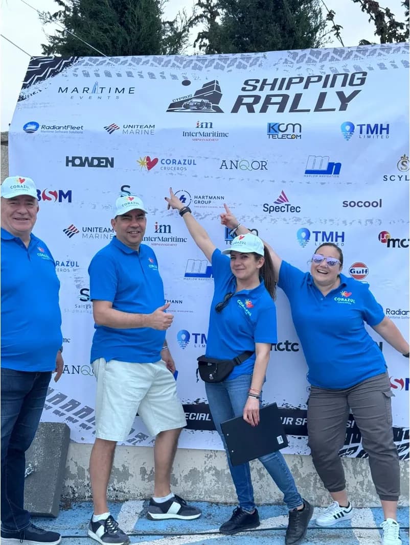 Sponsors in matching blue shirts posing at the rally backdrop
