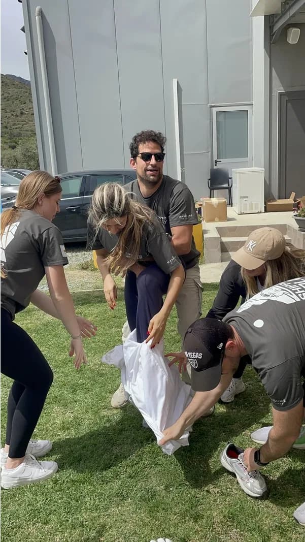A team helping each other into a beekeeper suit at the bee station